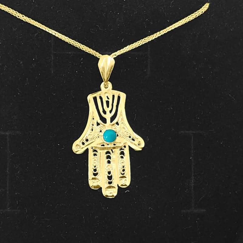 תליון חמסה(2.8*1.7 ס"מ) עם מנורה מזהב צהוב 14 קראט עם עיטורי פיליגרן מהממים ואבן טורקיז במרכזה. ניתן לרכישה עם או ללא שרשרת. מחיר מבצע מיוחד באתר מתנות ישראל.