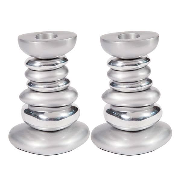 זוג פמוטים ( 8.5*5*11.5 ס"מ )פמוטים אלו עשויים מאלומיניום בגימור מט ומבריק מעוצבים ומיוצרים על ידי אומן היודאיקה הירושלמי יאיר עמנואל. העיצובים של עמנואל מבוססים על השילוב שבין המוטיבים המסורתיים הקלאסיים ובין המודרני והאוריינטלי. השראת פמוטים אלו מגיעה מתוך עולם הטבע וחלוקי נחל הנערמים. במחיר מבצע מתנות ישראל עם שליח עד הבית